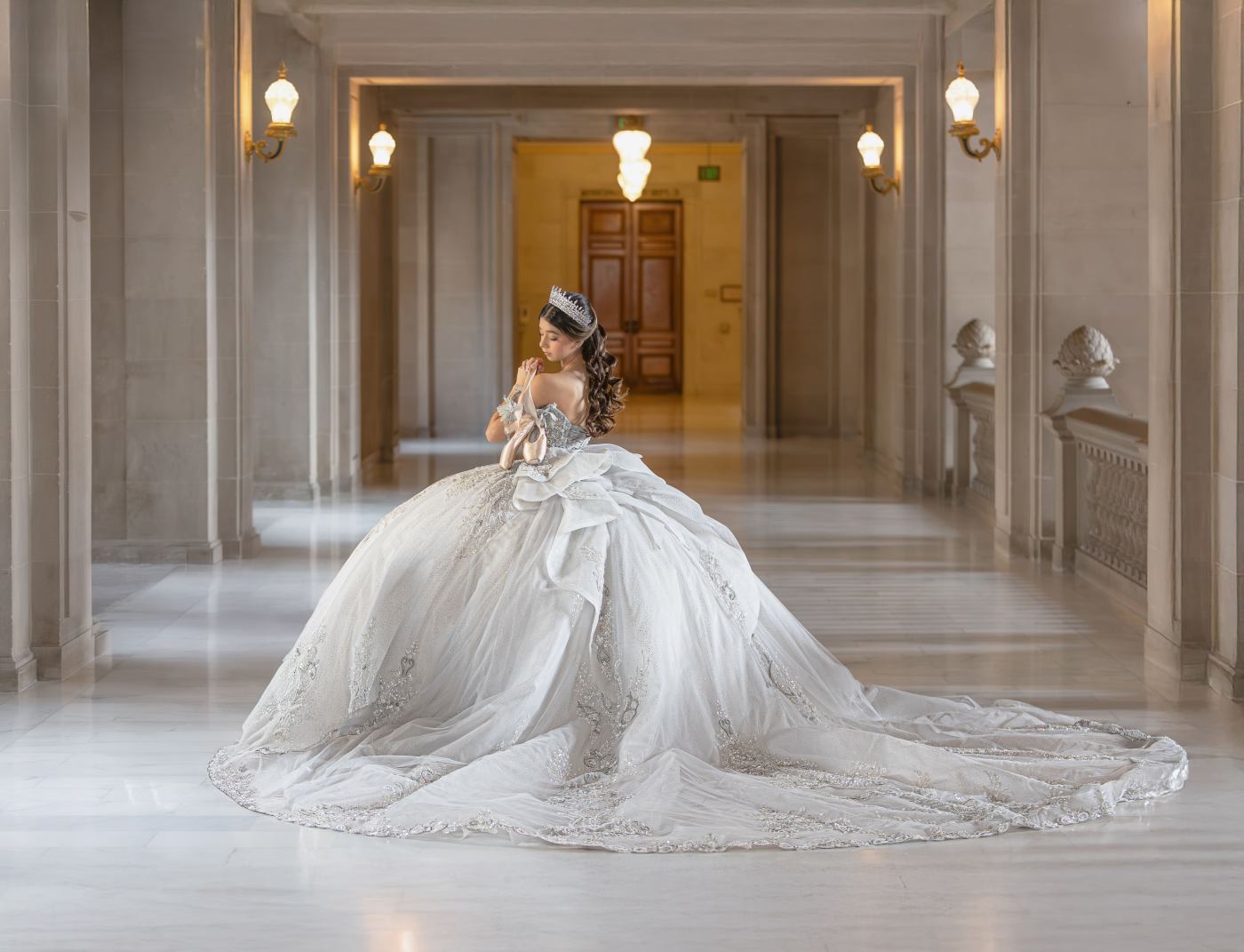 Quinceañera in a white gown inside an elegant hall